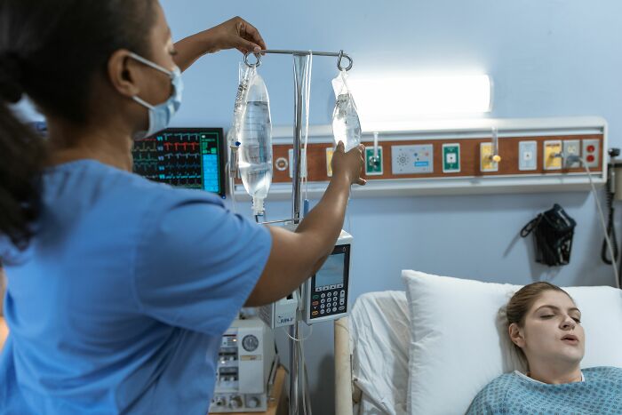 A nurse in a mask adjusts an IV drip for a patient lying in a hospital bed. People hid their true selves.