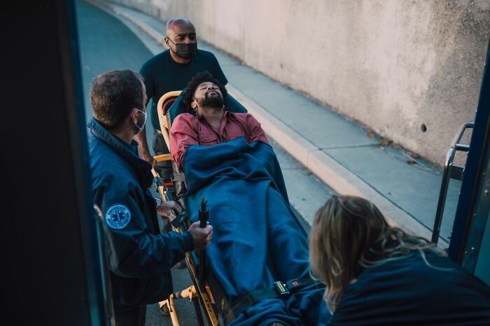 Paramedics are moving a man on a stretcher, an image conveying something creepy.