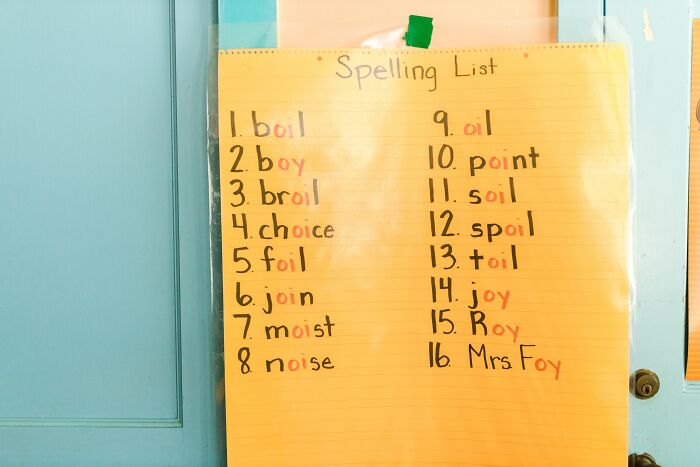 Handwritten spelling list on yellow paper taped to door for English spelling practice
