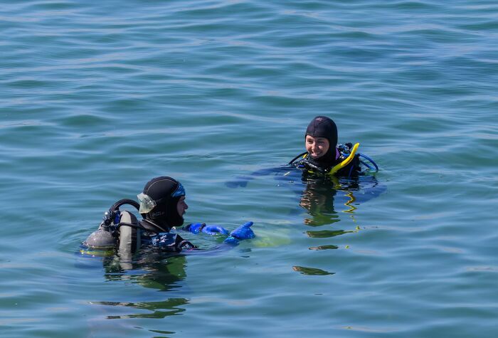 Two scuba divers communicating on water surface