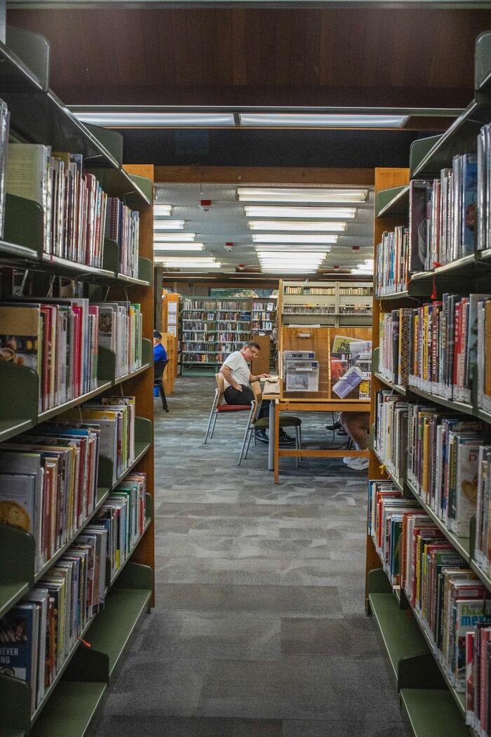 A library aisle with bookshelves and people studying, symbolizing true facts about knowledge and places.