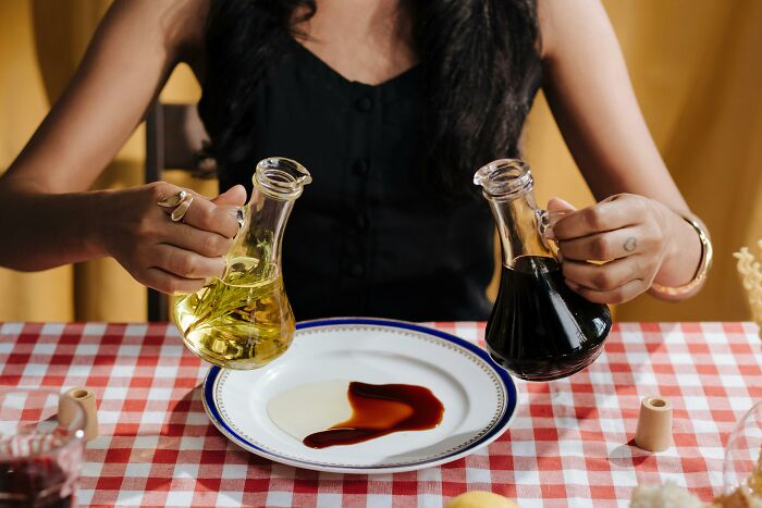 Person pouring olive oil and balsamic vinegar on plate food facts