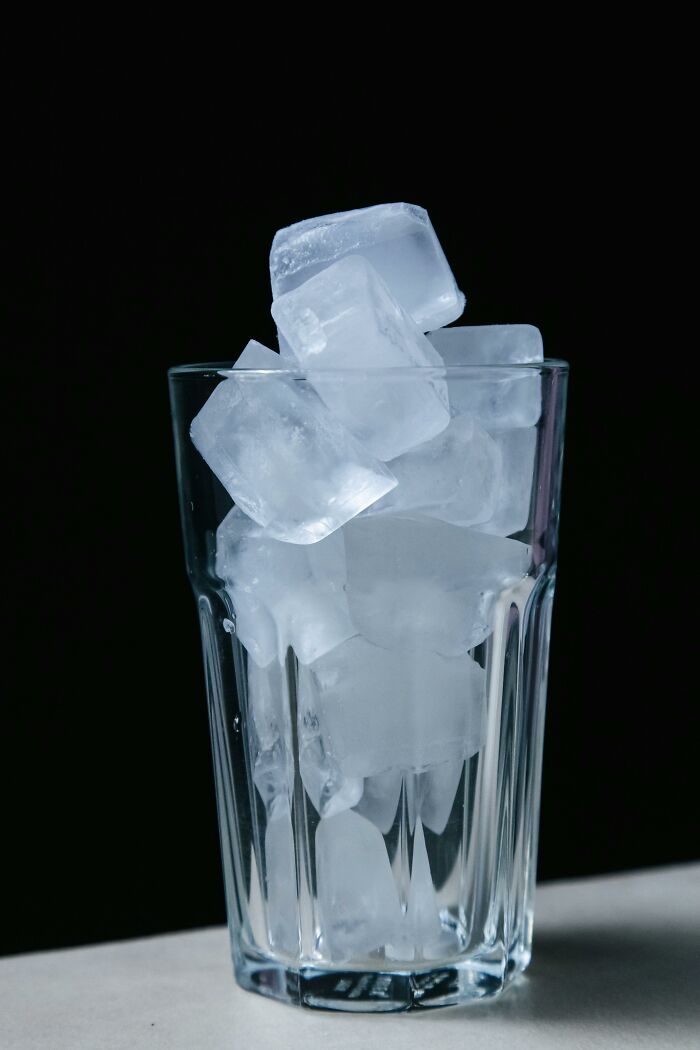 Glass filled with ice cubes against black background