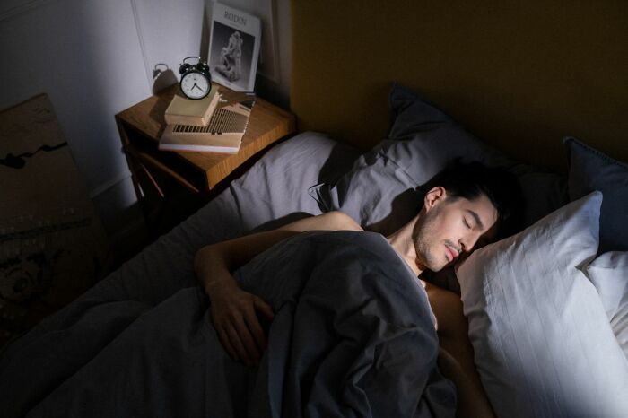 A man sleeping soundly in bed, unaware of what his partner might find on his phone.