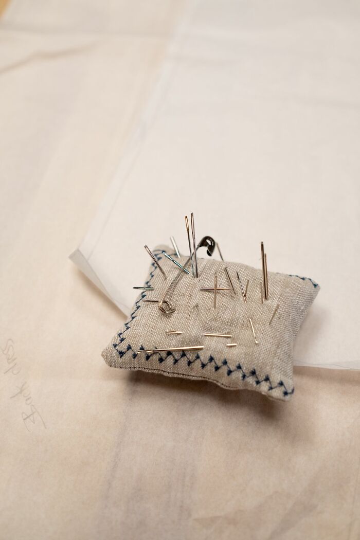 A pincushion with many pins and needles on a light surface, possibly from an unserious ER visit involving a crafting mishap.