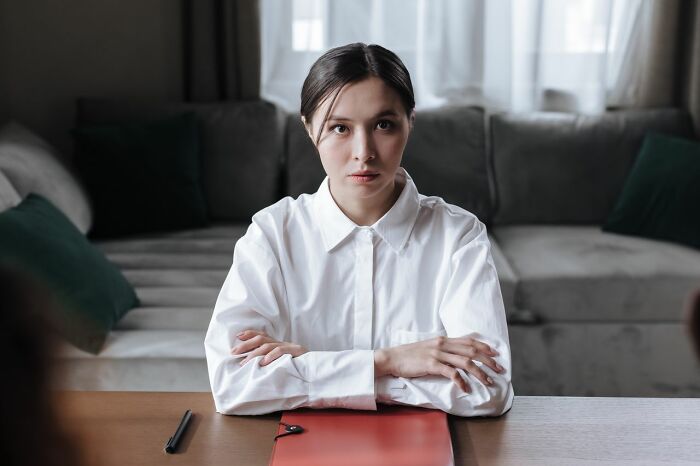 Woman looking serious at table with folder and pen indoors