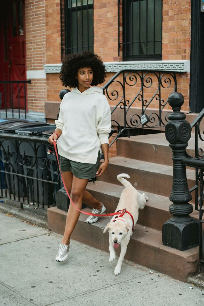 Woman walking dog outside a city building in casual wear