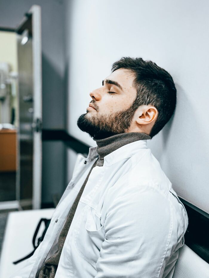Man resting with eyes closed against wall