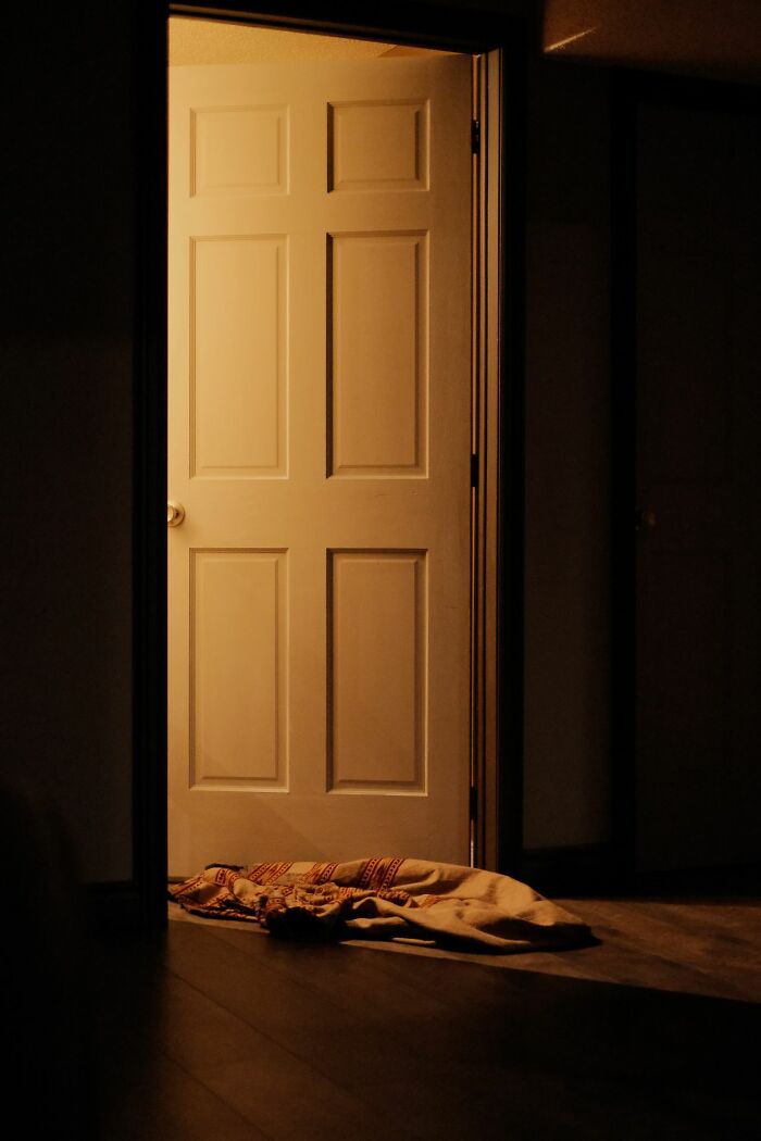Partially open door with warm light shining into dark room and blanket on floor