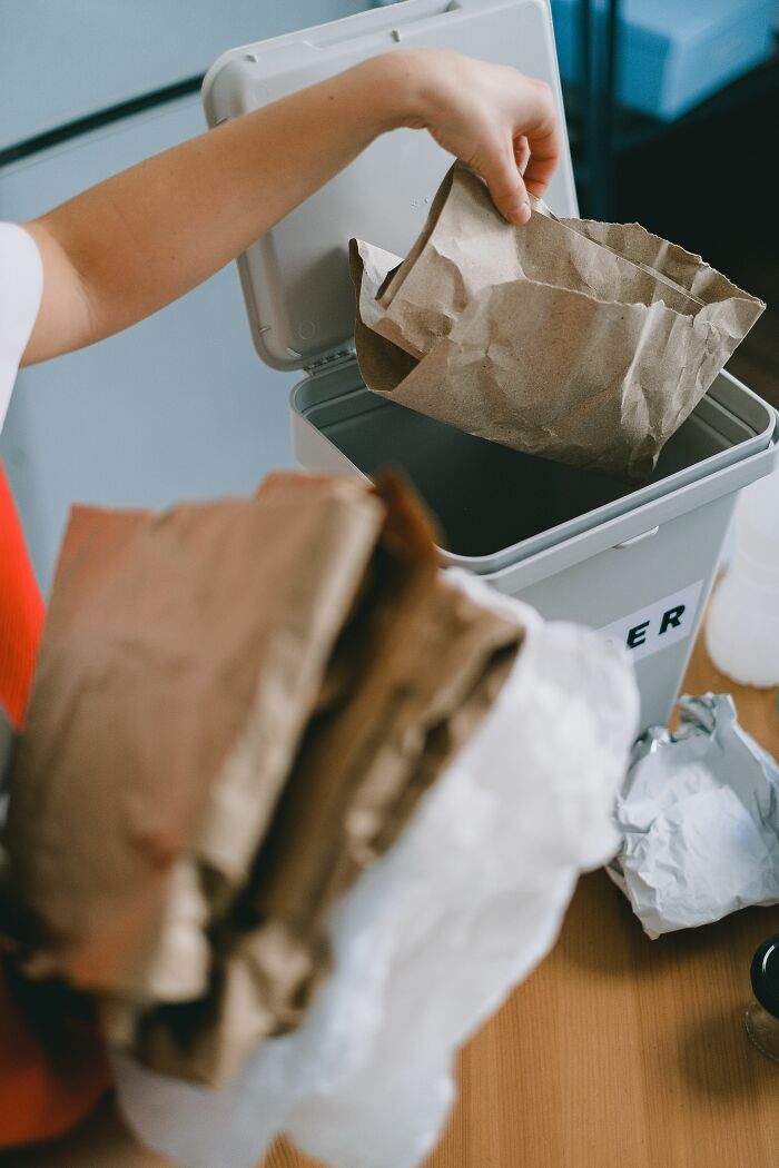 Person placing paper recycling into bin at home