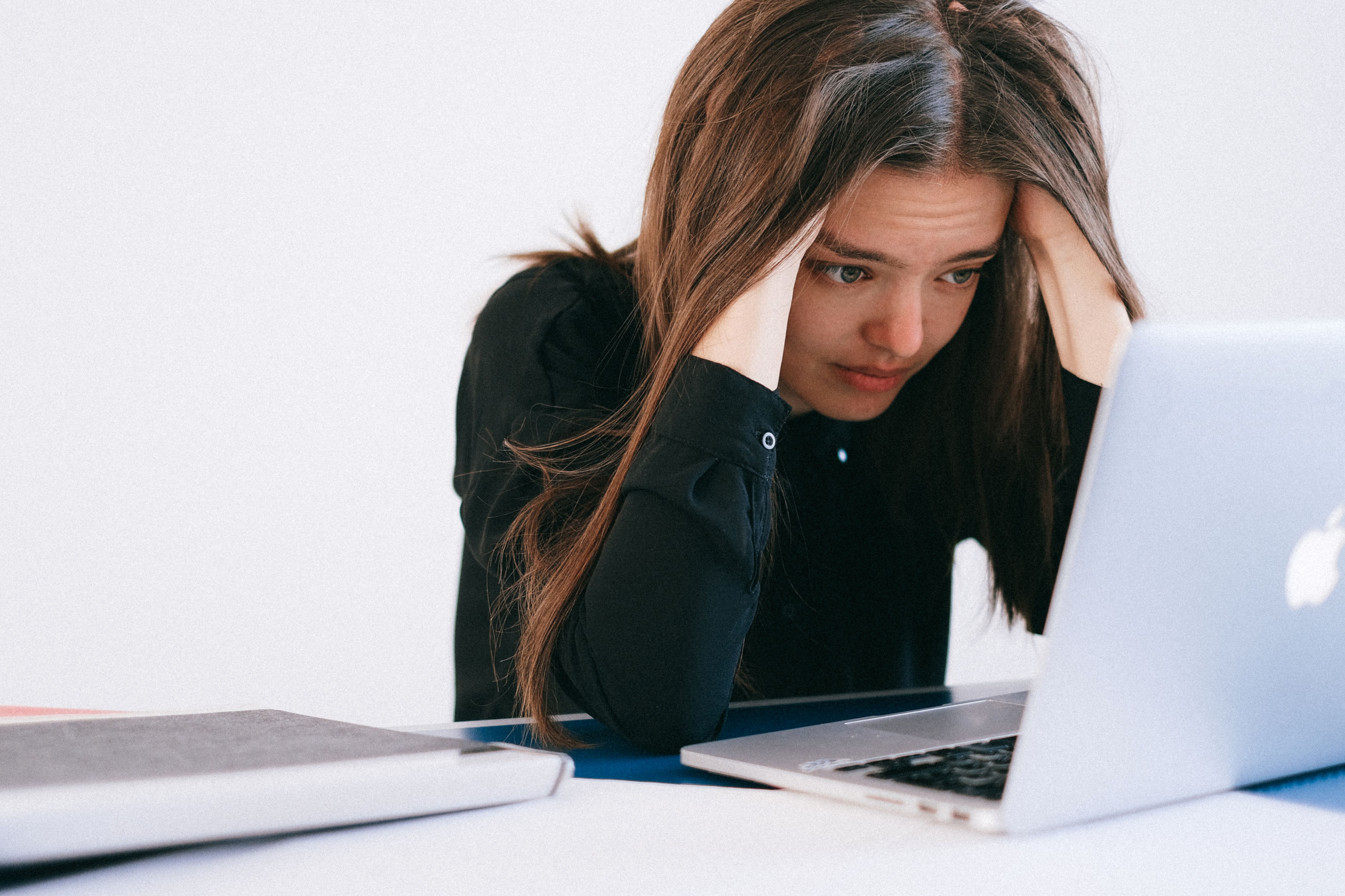 Stressed woman holding her head looking at laptop screen wedding planning issue