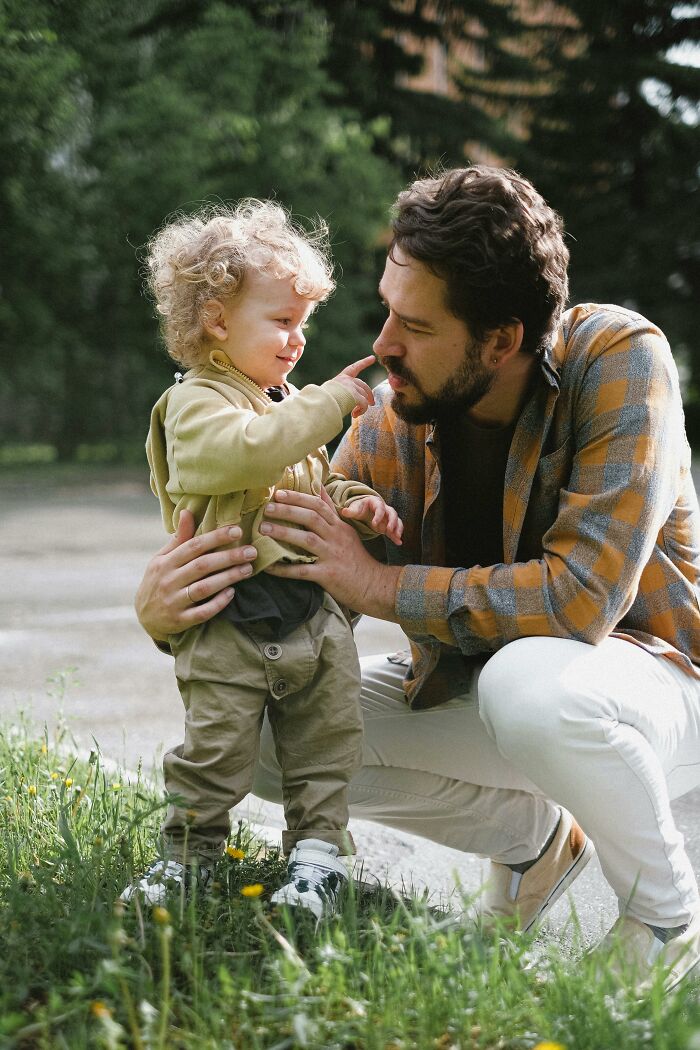 Toddler playfully touching father's nose outdoors parenting moment