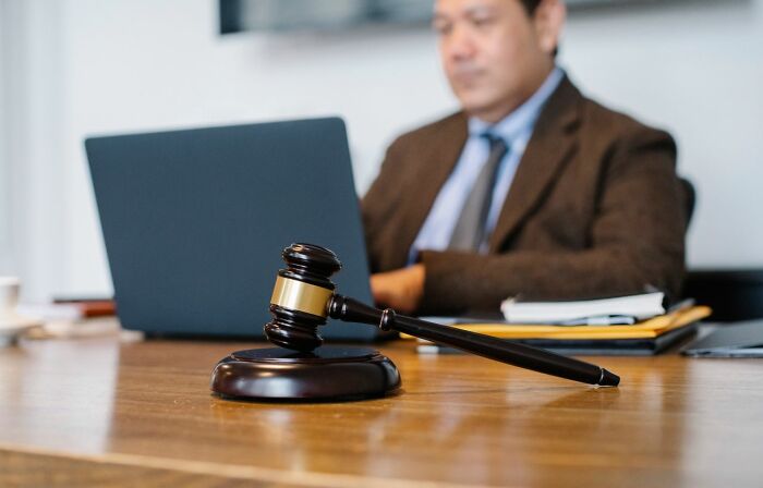 A gavel resting on a desk with a lawyer working on a laptop in the background, symbolizing courtroom stories.
