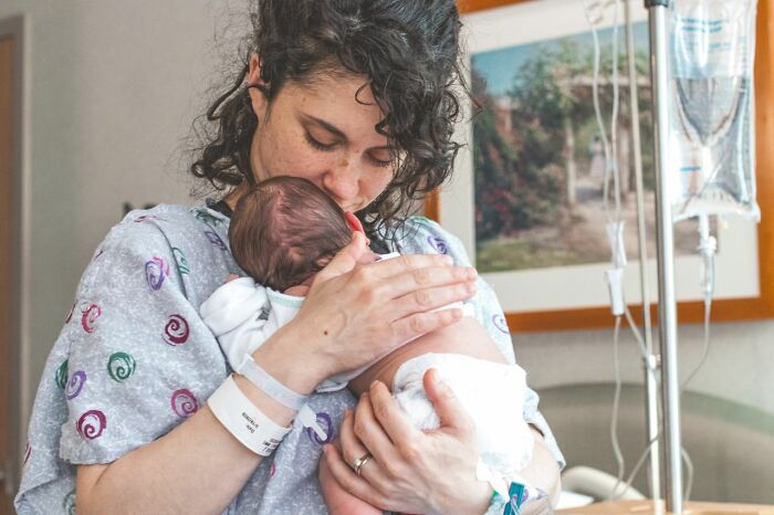 A new mother cradling her newborn baby, experiencing a unique type of pain and love.