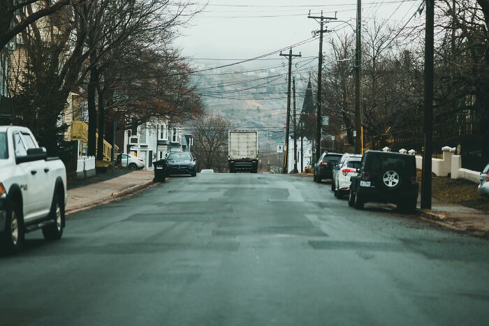 A street with cars parked on the side and a truck in the distance, portraying the idea of people who hid their true selves.