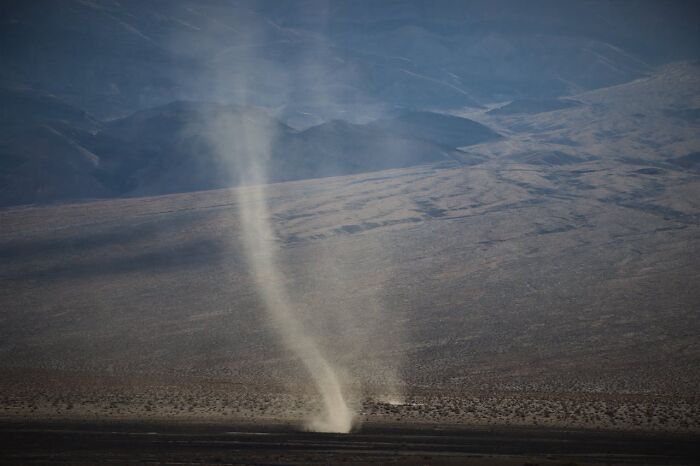 Desert tornado swirling dust with mountain backdrop natural disaster
