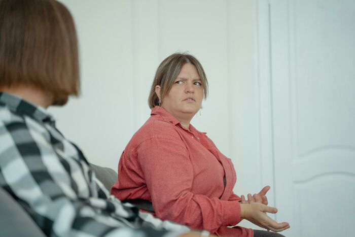 Woman in red shirt discussing seriously with another person
