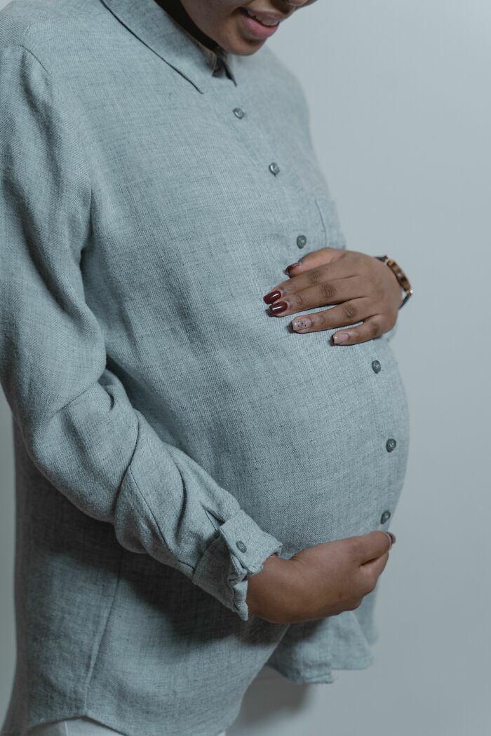 A pregnant woman holding her belly, showcasing human bodies and facts.
