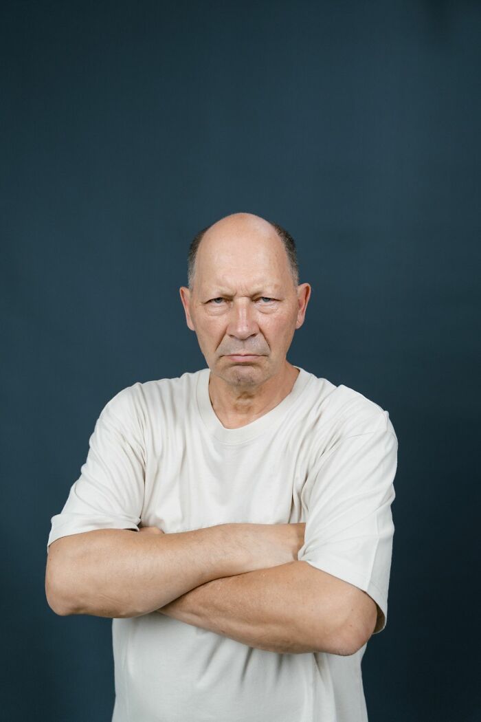 Grumpy bald man with folded arms and serious expression
