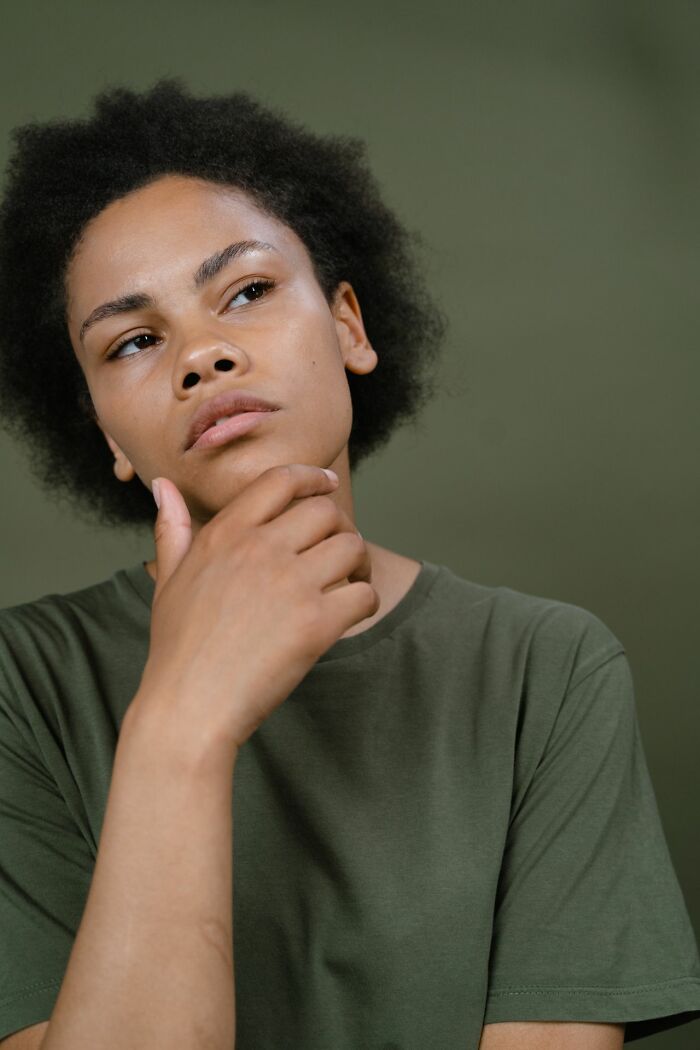 A person with afro hair secretly very smart and thinking, showing hints of intelligence.