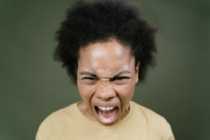 A person with an afro and a yellow shirt screaming in full rage mode, having snapped and couldn't take it anymore.