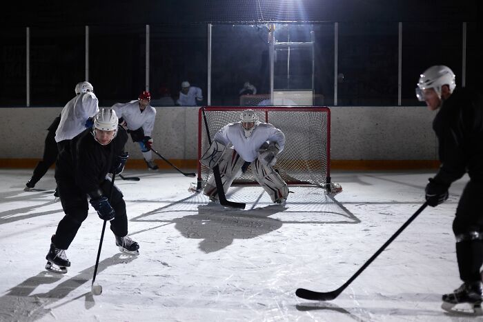 An ice hockey goalie in a white uniform blocking a puck, with players around him, representing a rage mode.
