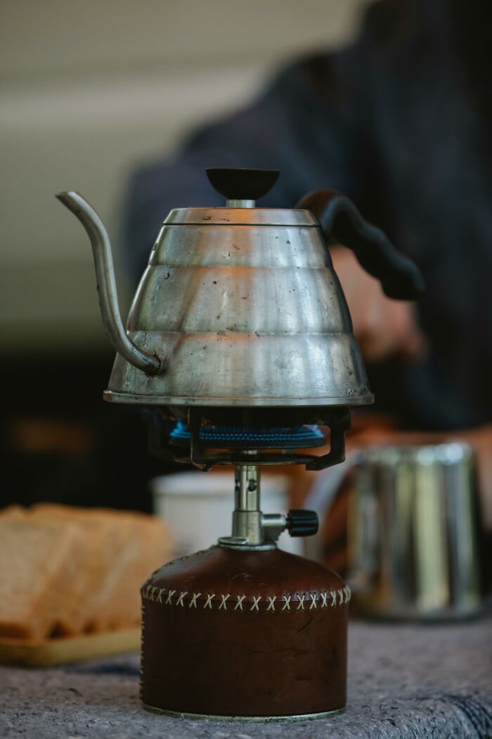 Vintage metal teapot on portable gas stove with stitched leather base