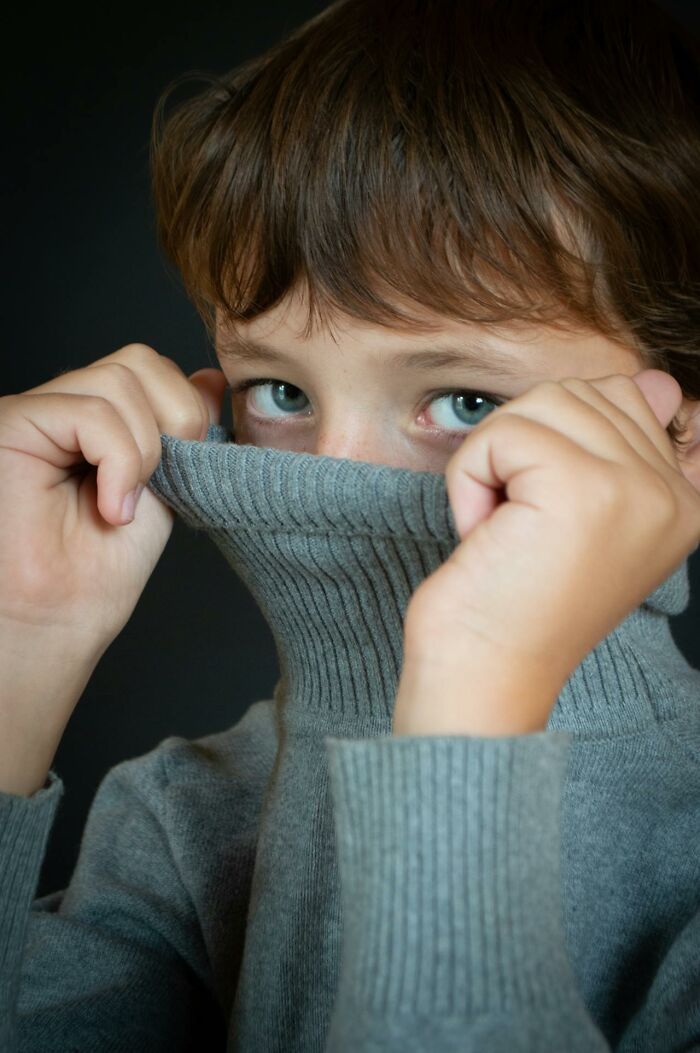 Child pulling sweater up over face showing blue eyes