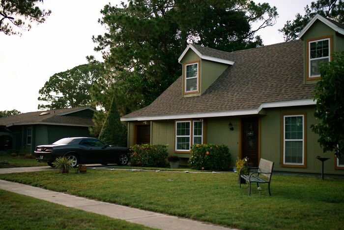 A green house with a dark car parked in the driveway. The car and house represent strange coincidences that happened to people.