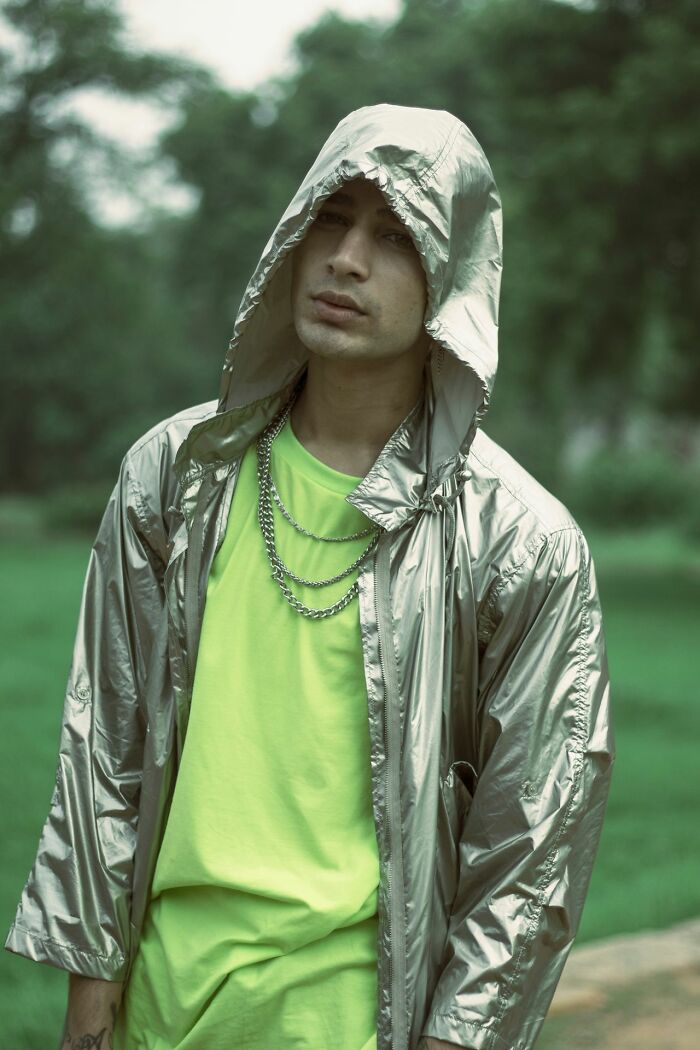 A man in a silver hooded jacket and lime green shirt, reflecting experiences people can't explain.
