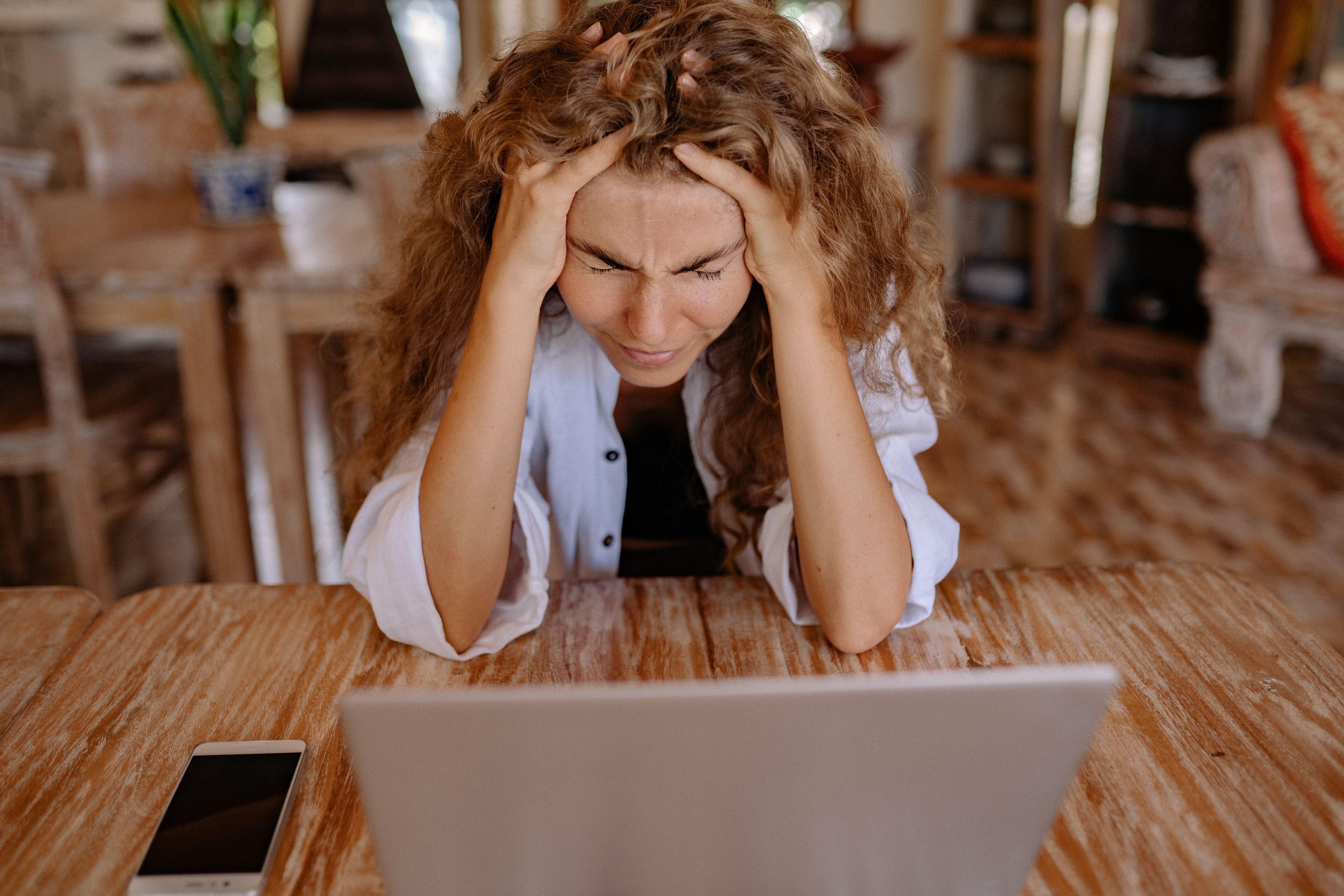 Woman holding head in frustration at laptop showing wedding stress
