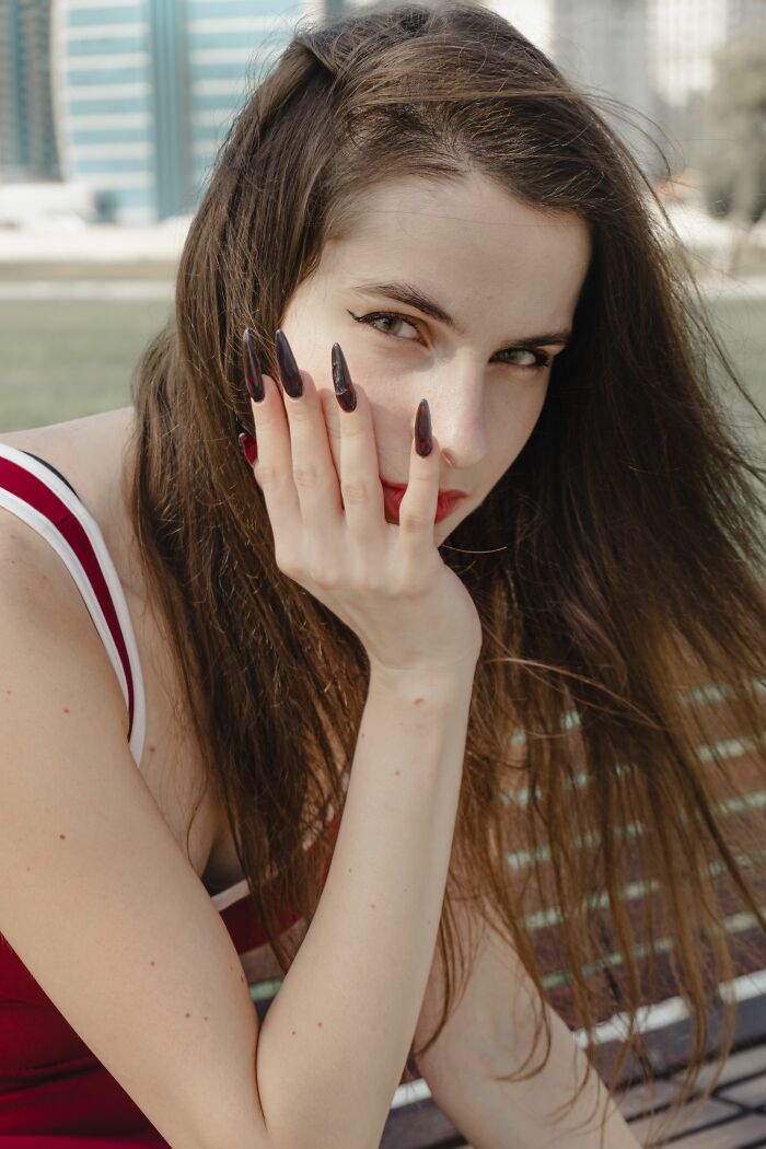A woman with long dark hair and striking nails gazes directly at the camera, embodying a potential turn off.