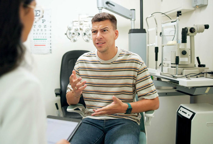 Frustrated man consulting licensed optician during eye exam