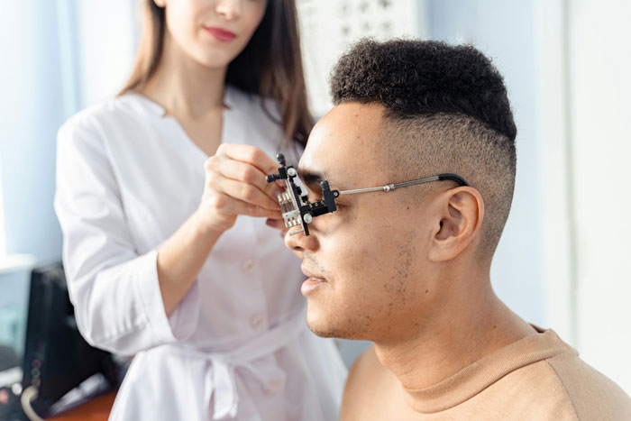 Licensed optician fitting glasses frame on customer during eye examination