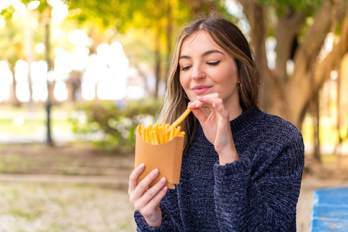 A picky eater girlfriend enjoying french fries in a park, illustrating a common relationship challenge. A picky eater girlfriend enjoying french fries in a park, illustrating a common relationship challenge.
