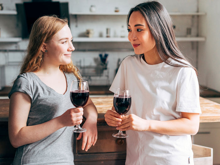 Two young women drinking wine and discussing parenting outsourcing Two young women drinking wine and discussing parenting outsourcing