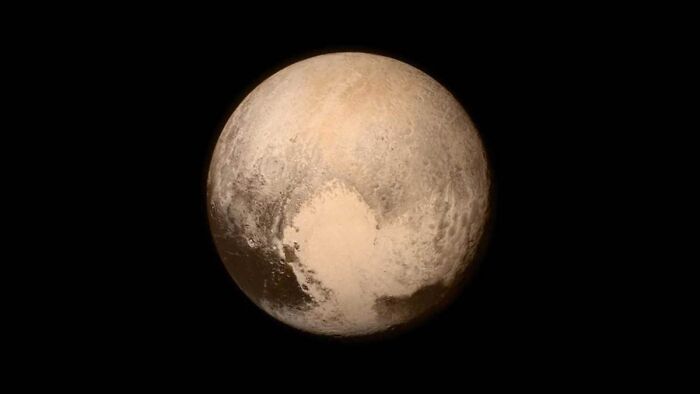 A close-up view of Pluto, showcasing its surface details and coloration, a crazy but true fact about planets.