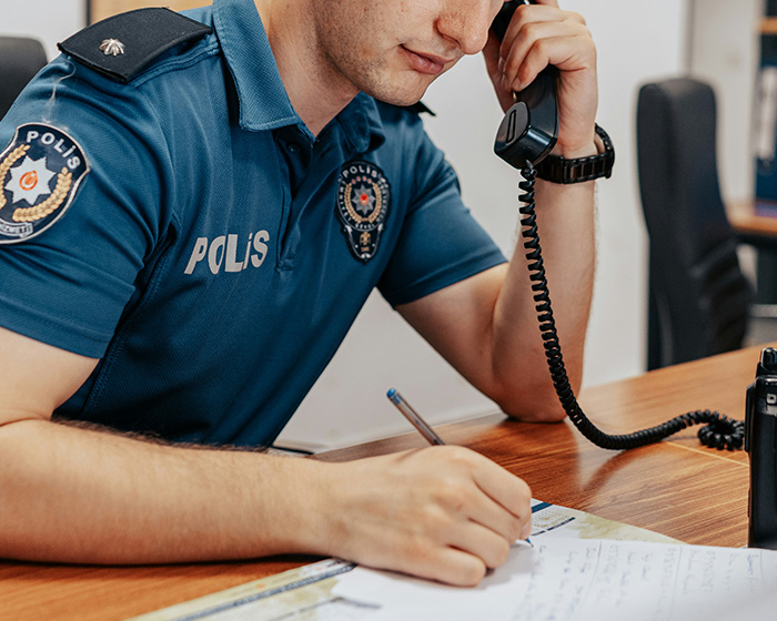 A police officer on the phone, taking notes after a man discovers a classmate's fake photos and is traumatized. A police officer on the phone, taking notes after a man discovers a classmate's fake photos and is traumatized.