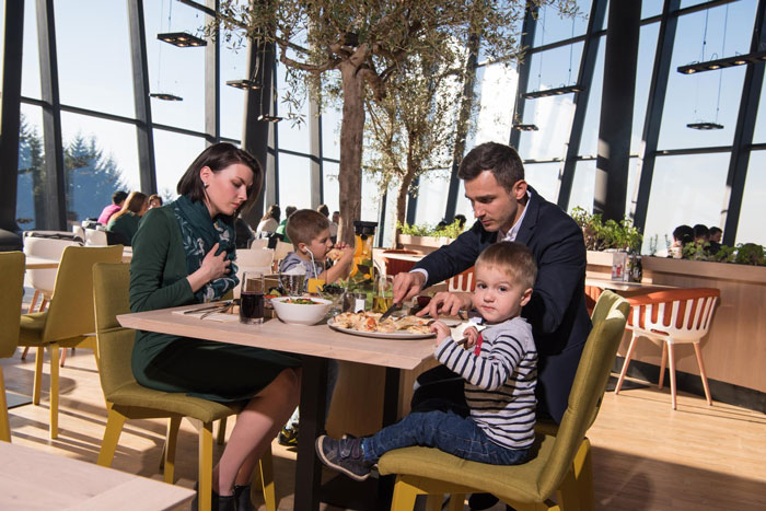 A family with two children dining in a modern restaurant, illustrating a pregnant woman working in a pub setting.