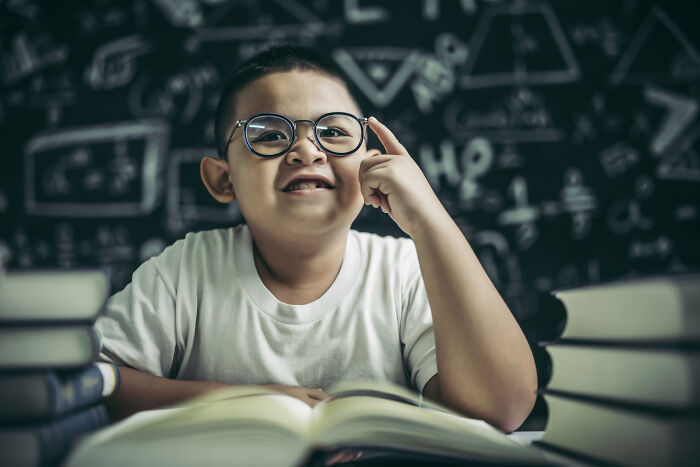 Primary boy wearing glasses thinking in study environment