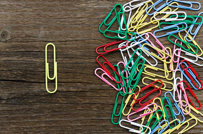 Close-up of colorful paperclips with one yellow paperclip apart