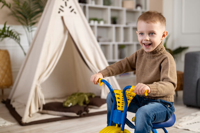 Happy primary boy riding toy bike demonstrating behavioral traits
