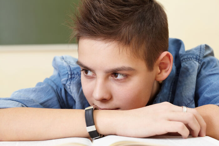 Primary child looking away while resting chin on arm