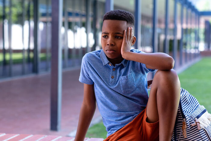 Primary boy sitting outside looking upset and distressed