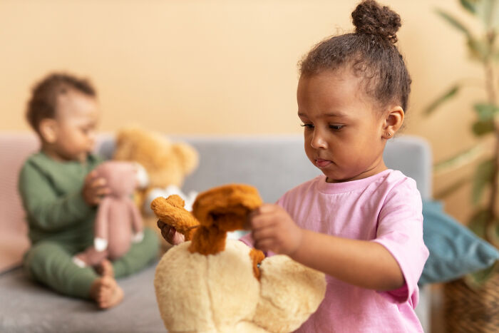 Primary girl playing with teddy bear showing troubling behavior