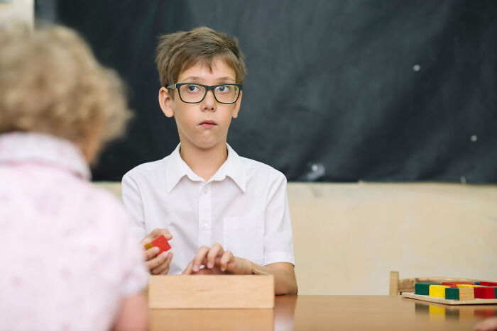 Primary boy with glasses playing with blocks showing psychopathic behavior