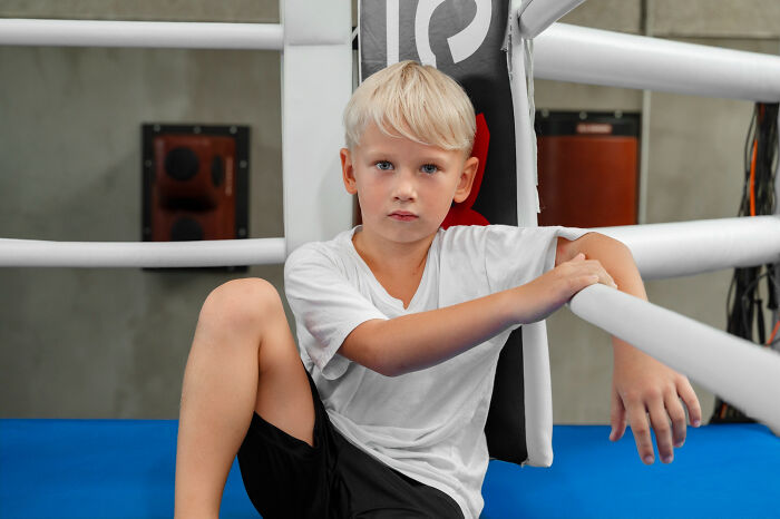 Primary child seated in boxing ring showing serious expression