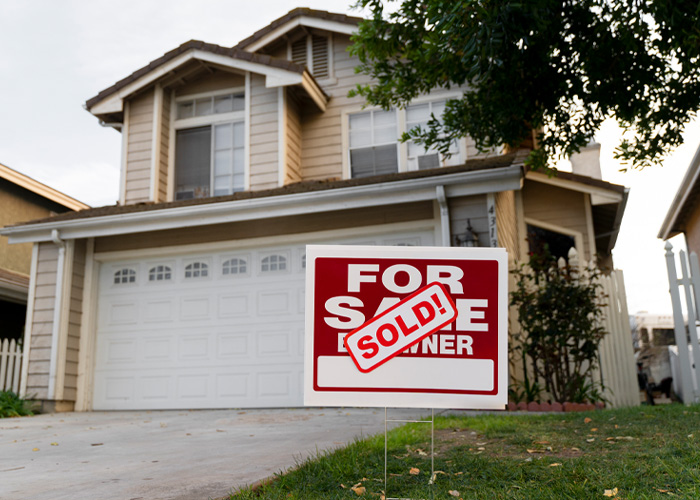 A FOR SALE sign with SOLD sticker in front of a house, relevant to homeowner warnings.
