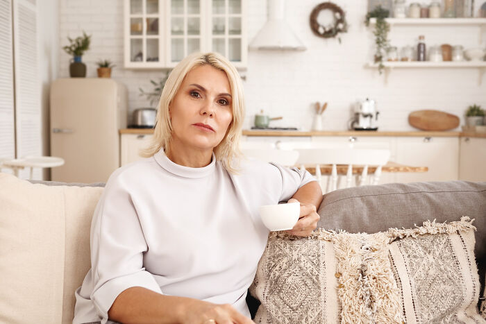 Thoughtful woman holding coffee cup in modern living room psychopathy signs concept