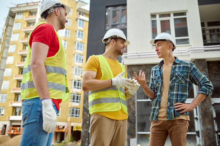Construction workers in safety gear discussing project meeting a psychopath